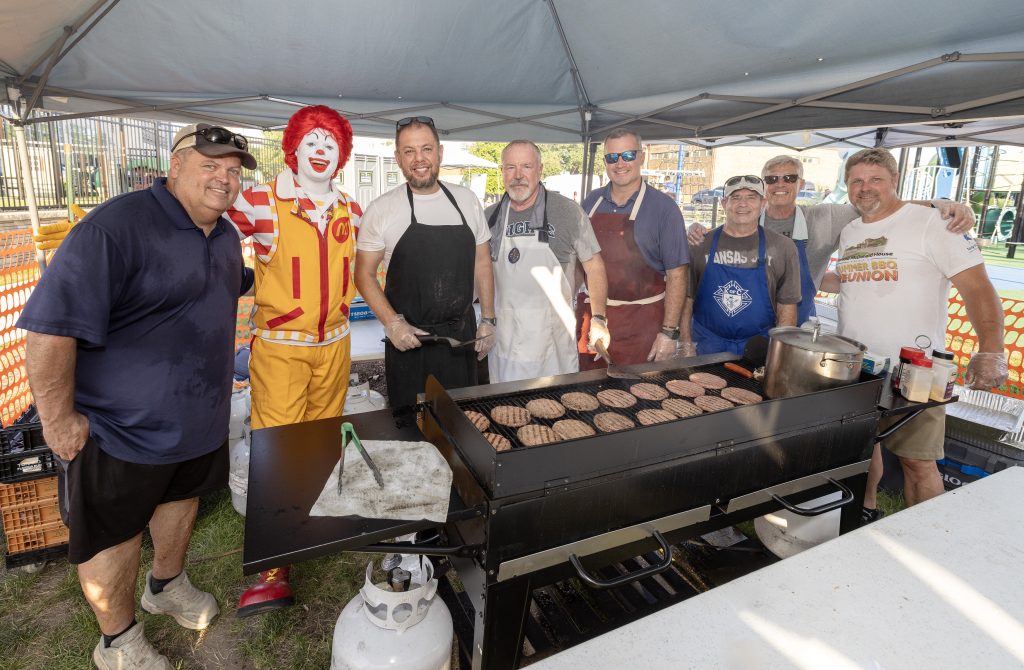 Volunteers grill burgers with Ronald McDonald under a tent at the Ronald McDonald House Summer BBQ Reunion.