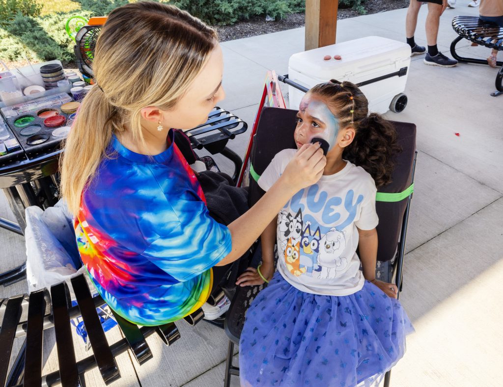 A young girl smiles as she gets her face painted at the Ronald McDonald House Summer BBQ Reunion.