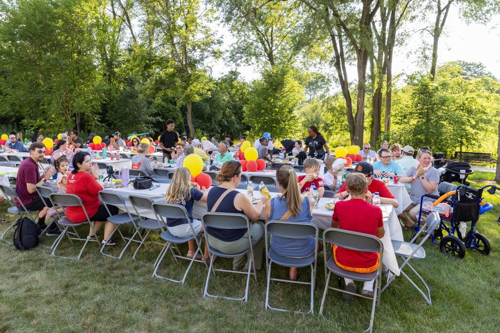 amilies gather at long tables for a meal at the Ronald McDonald House Summer BBQ Reunion.