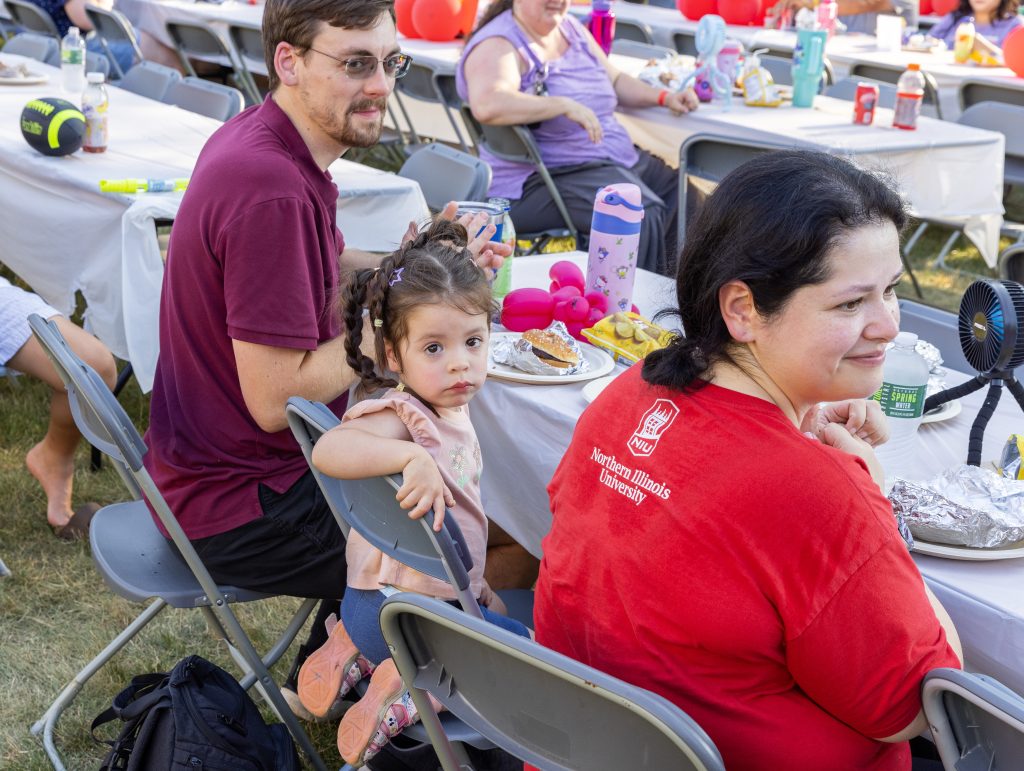A family sits together enjoying food at the Ronald McDonald House Summer BBQ Reunion.