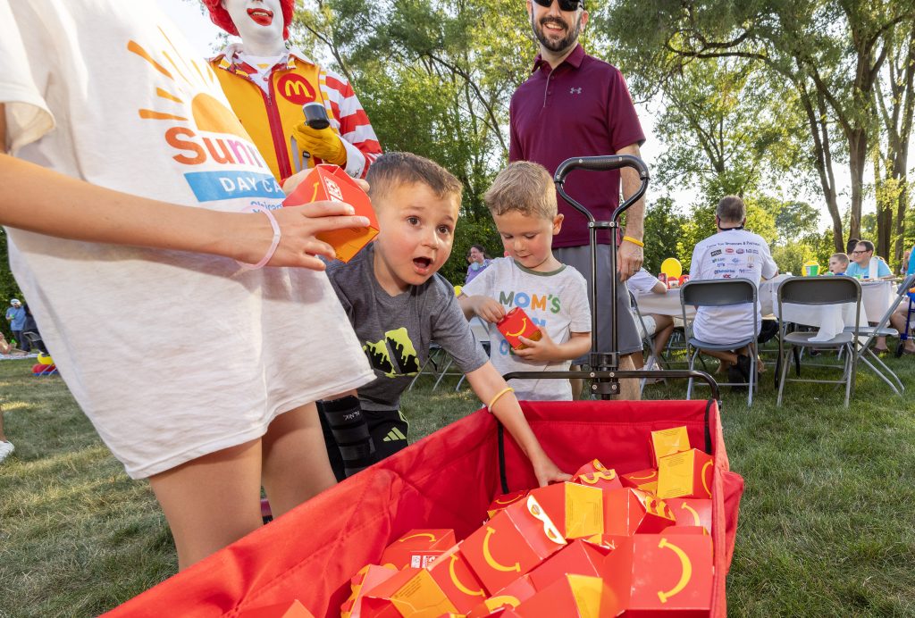 Ronald McDonald laughs with three young guests at the Summer BBQ Reunion.