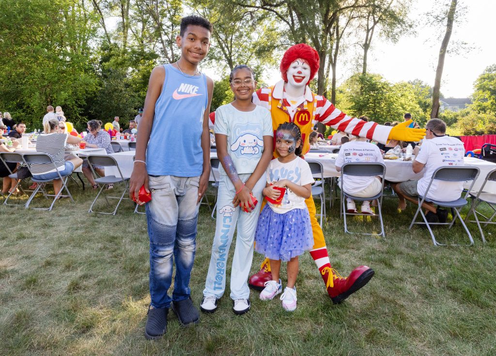 Three children pose with Ronald McDonald at the Summer BBQ Reunion.