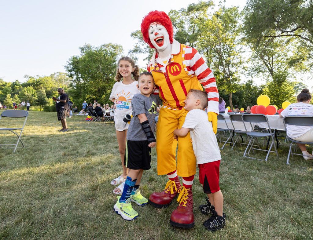 Three children pose with Ronald McDonald at the Summer BBQ Reunion.